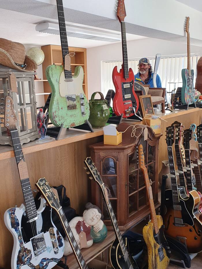 Die weisse Gitarre  im Vordergrund stellt eine Schneelandschaft mit dem Bergbach «Aua da Laider» in Tschierv dar.